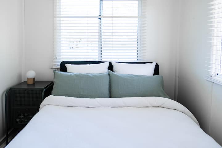A petite second bedroom that just fits a super comfortable Queen size bed, two little bedside tables, a full length mirror, fan or heater, and two guests! Guests can also hang their clothes on hooks ,and use the space,  in the adjoining front hall.