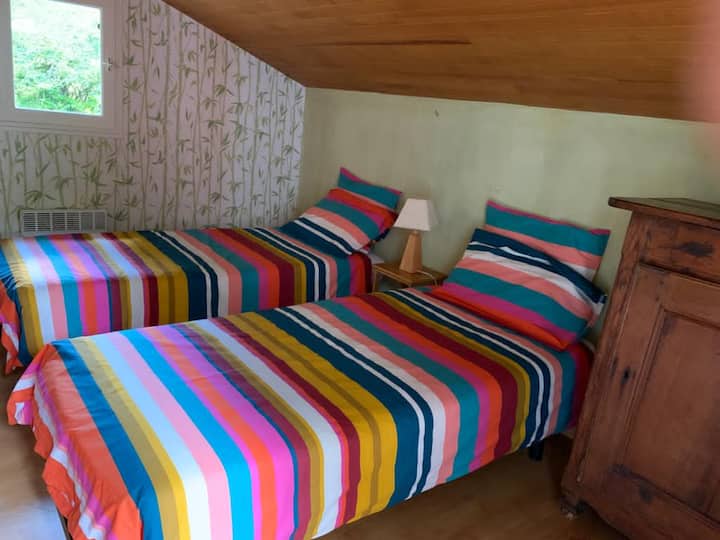 חדר השינה הראשון עם שתי מיטות משקיף על הגינה מצד אחד והשני למרפסת שאליה ניתן לגשת ישירות דרך דלת חלון