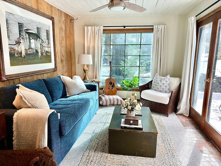Living area of first floor guest house with Queen size pull out, AC, and TV. French doors lead to backyard and Basket ball Court