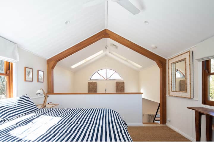 Glavna spavaća soba na međuspratu s bračnim krevetom i pogledom na vrt i jezero od 270 stupnjeva.