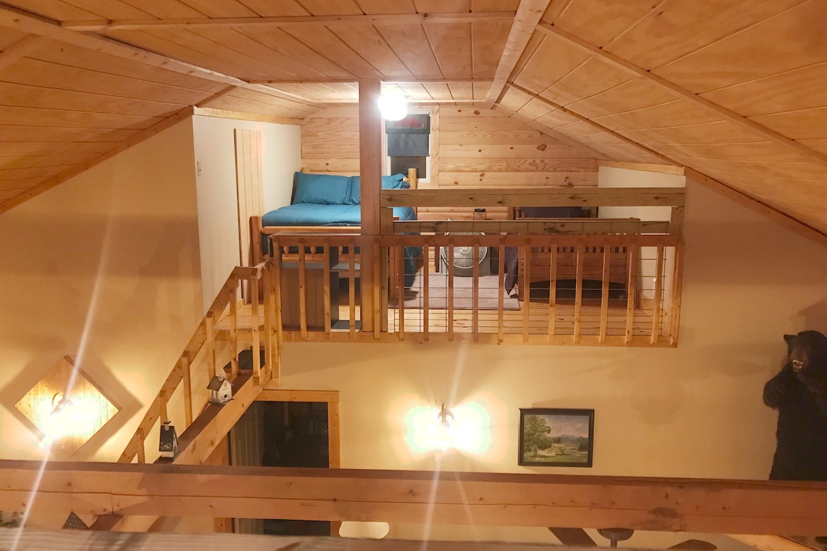 The loft sleeping room is viewed from the other loft sleeping room. Each loft has a full and twin-size bed and adjustable privacy screen, games, and books for entertainment.
