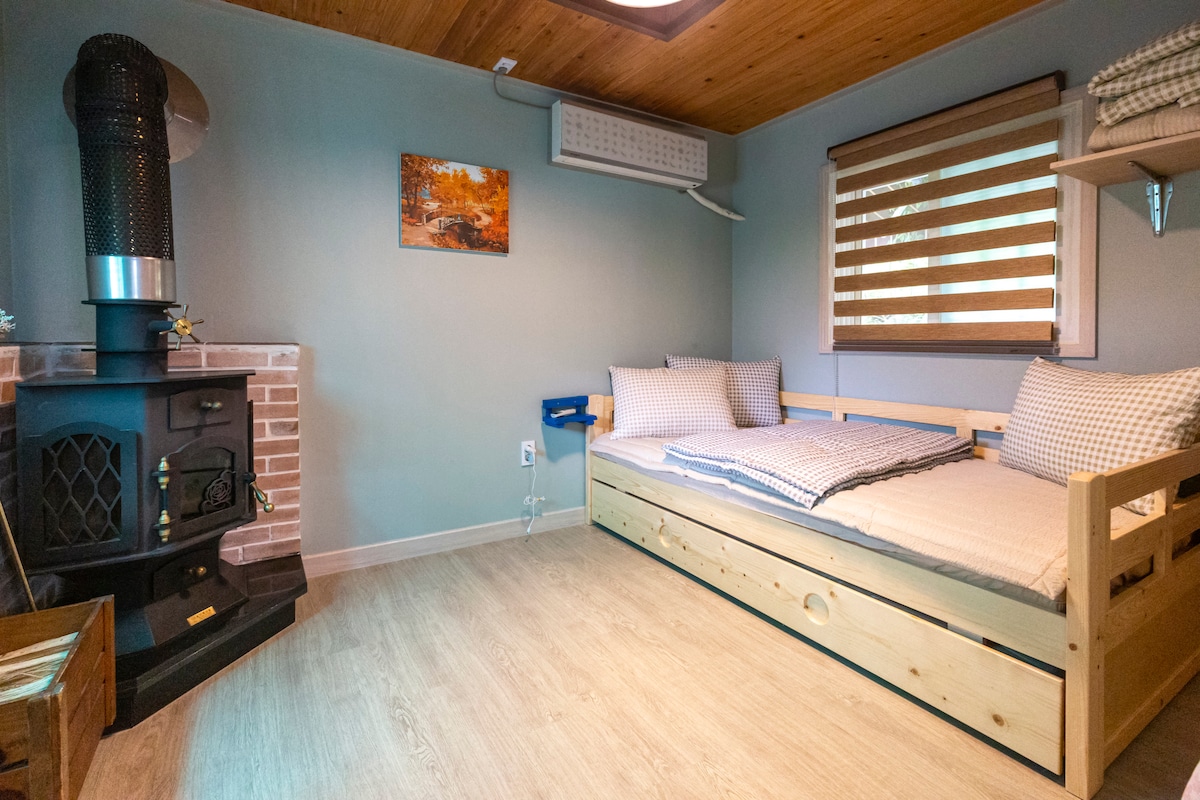 Es una habitación con cama con cuerpo verde. La cama está hecha de dos niveles, por lo que si retiras la cama de la parte inferior con la mano, saldrá otra cama. Es una cama que compré después de pensar en cómo usar el espacio pequeño de manera eficiente. Quiero que sea cómodo para los huéspedes que visitan.