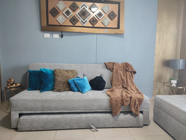 Dhomë ndenjjeje e gjerë me divan-krevat dhe krevat, konsolë videolojërash dhe lojëra tavoline