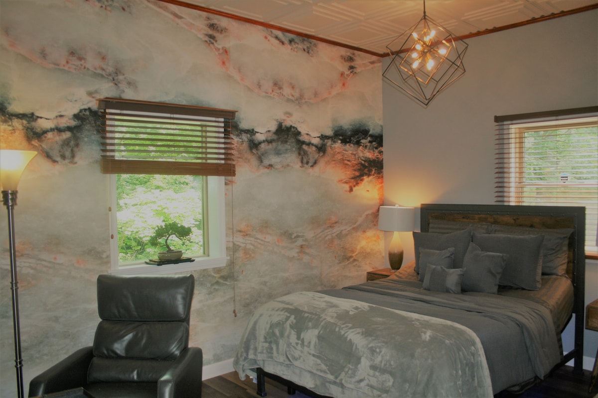 Barcalounger swinger reclinable, cama tamaño queen moderna, industrial urbana. Lámparas bellamente sopladas encima de las mesitas de noche de madera de acacia. Cama de espuma viscoelástica híbrida de 15 pulgadas. Edredón Ugg, estúpido alto número de hilos y sábanas y fundas de almohada de algodón turco. 