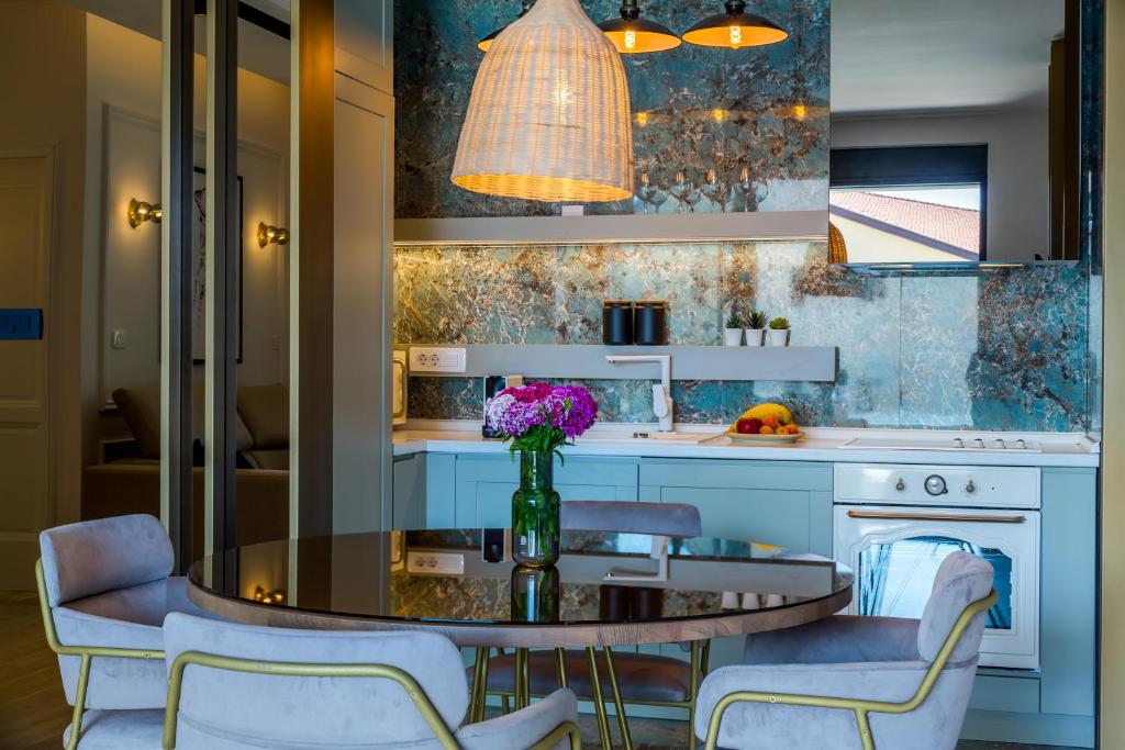 An open kitchen and dining area features a round table surrounded by four upholstered chairs. A modern kitchen with a stylish backsplash includes essential appliances. A pendant light illuminates the space, while a vase of colorful flowers adds a touch of elegance.