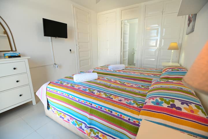 Camas individuales con baño privado con sábanas suaves de colores brillantes... almohadas cómodas para un sueño encantador, lámparas laterales para un tiempo de lectura relajante.