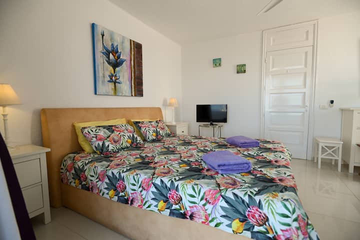 Dormitorio cómodo con ropa de cama de flores. La funda de la cama con flores da mucho color a la habitación que coincide con la pintura de la pared sobre la cama.