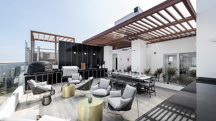 A spacious rooftop terrace is featured, equipped with modern seating arrangements and a dining area. The space is complemented by a grill station, potted plants, and stylish outdoor furnishings, providing a panoramic view of the surrounding area.