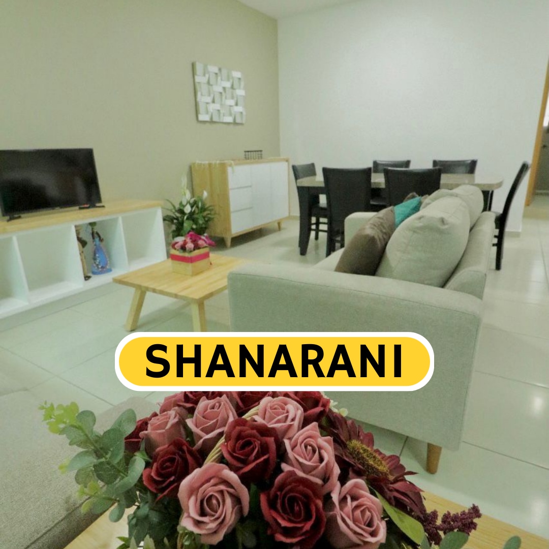 A modern living space features a comfortable sofa, a wooden coffee table, and a dining area with black chairs. A flat-screen television is placed on a white media unit. A bouquet of flowers adds a touch of color to the setting.
