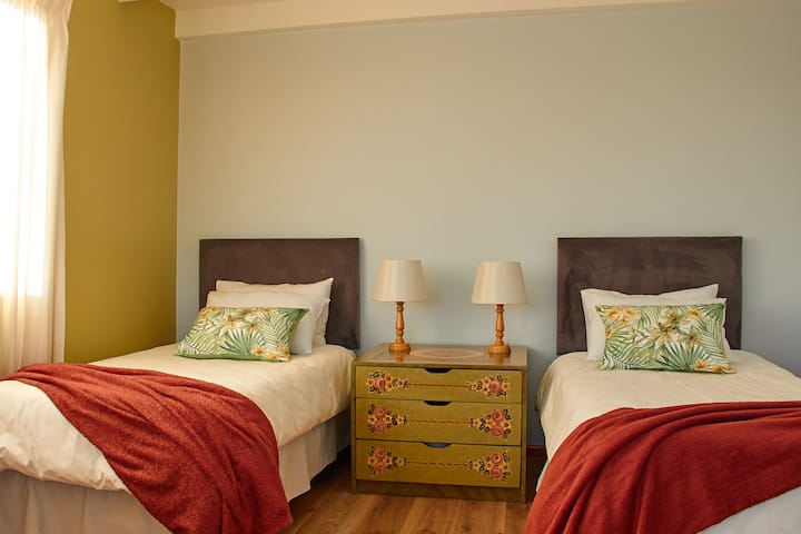 Second bedroom, generously sized with twin beds, a seating area and attached balcony with a view of Table Mountain.