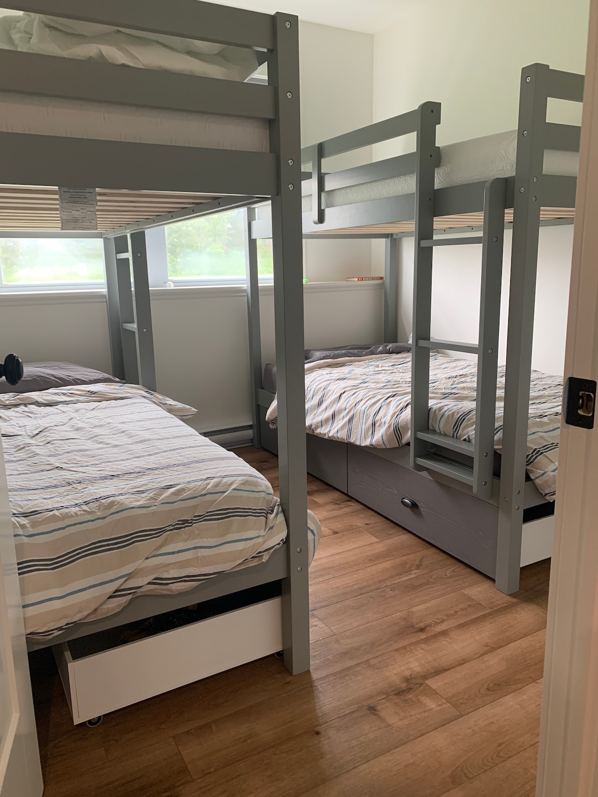 Habitación con literas en el nivel inferior con 4 camas y cuatro cajones de almacenamiento bajo la cama.