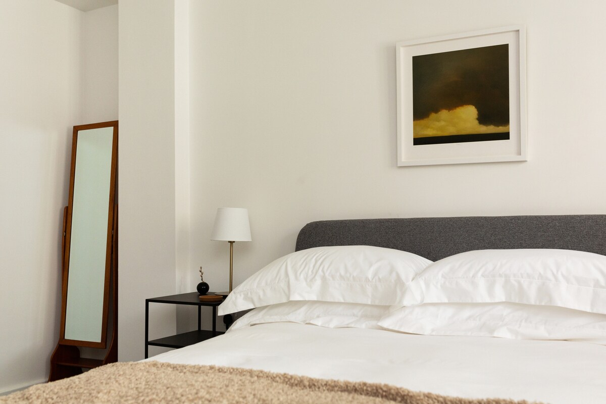 In the back bedroom, a picture by local artist – Ned Kelly – sets the scene. Crisp white Egyptian cotton sheets, plenty of pillows, soft lighting, and shutters. A Casper mattress makes for restful sleep. 
