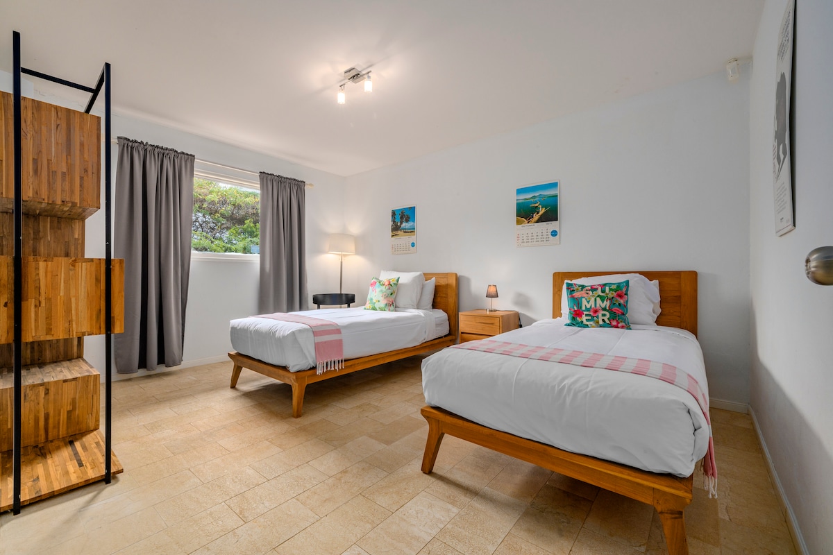 Ova spavaća soba ima osvijetljenu unutrašnjost , dva kreveta za jednu osobu, klima-uređaj i crni stalak s lampom. Postoje velike zavjese za privatnost