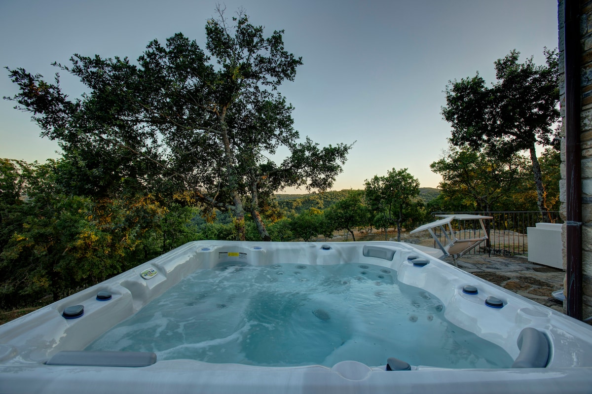A view of a hot tub is presented against a backdrop of trees and rolling hills. The water is still, inviting relaxation, while the horizon showcases the natural beauty of the surrounding landscape.