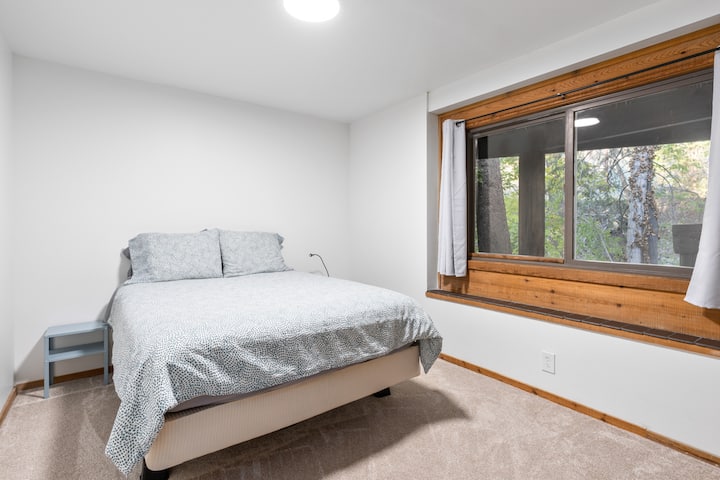 غرفة نوم في الطابق السفلي بسرير بحجم ملكي وإطلالة على الجدول. 