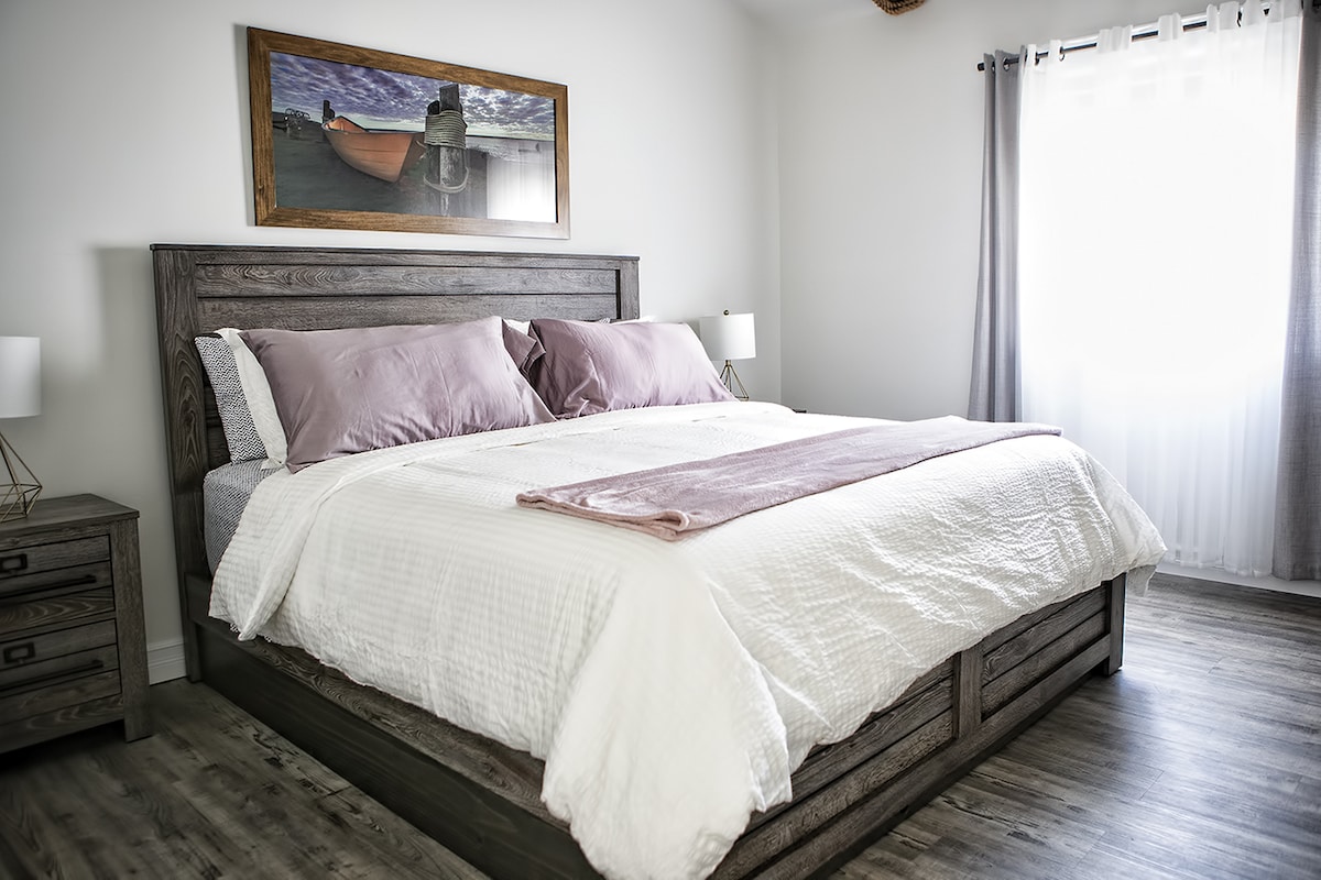 Kitanda cha ukubwa wa king chenye starehe katika chumba kikubwa cha kulala kilicho na dirisha la kuongeza giza