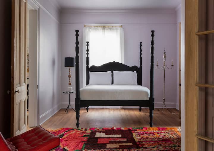 מיטת קווין סייז אירופאית עתיקה, עם מאוורר תקרה מעליה ושטיח ברבר מרוקאי על הרצפה. 