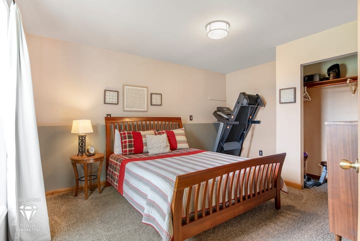 Downstairs Bedroom, with Comfortable Queen Bed, dresser, Tv and workout equipment.
