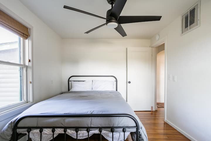 Welcome to the cozy second bedroom, featuring a queen bed with a Casper memory foam mattress, ensuring a restful night's sleep. This charming room is equipped with blackout blinds on both sets of windows for complete privacy and a peaceful slumber.