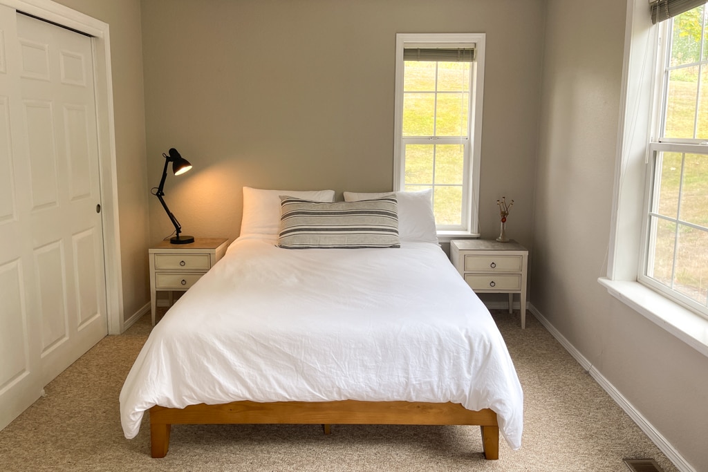 Спална соба бр. 3 со брачен кревет со поглед на зимзелените дрвја во предниот двор.