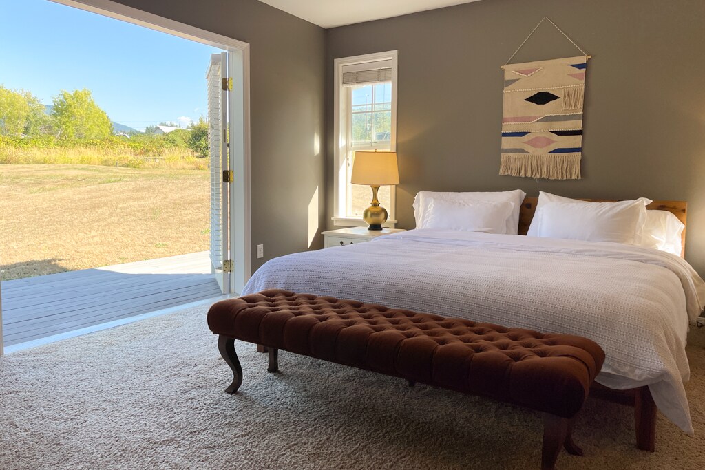 Главна спална соба со брачен кревет со поглед на задниот двор од 1 декар со зимзелен и поглед кон планината.