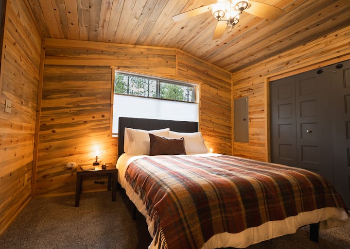 Bedroom downstairs features a queen bed, comfortable bedding, extra pillows, wool blanket, and a ceiling fan
