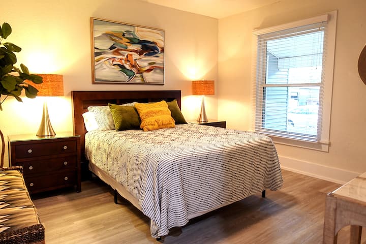 Un dormitorio tamaño queen cálido y acogedor con obras de arte originales e iluminación suave: el tipo de espacio de descanso que hace que un viaje fuera de casa se sienta cómodo y personal. (403)