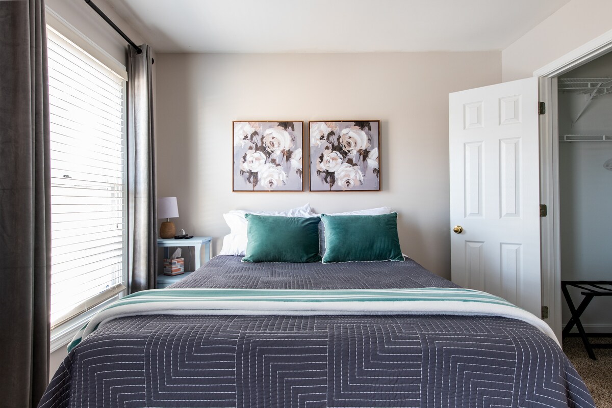 Bedroom 2 is located on the 2nd floor in the back of the home. It features a walk-in closet, desk, ceiling fan, queen sized bed, and Smart TV. 