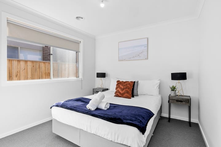 Ნათელი ოთახი გვერდითი მაგიდებით, ლამპებითა და ხელოვნების ჩარჩოთი.