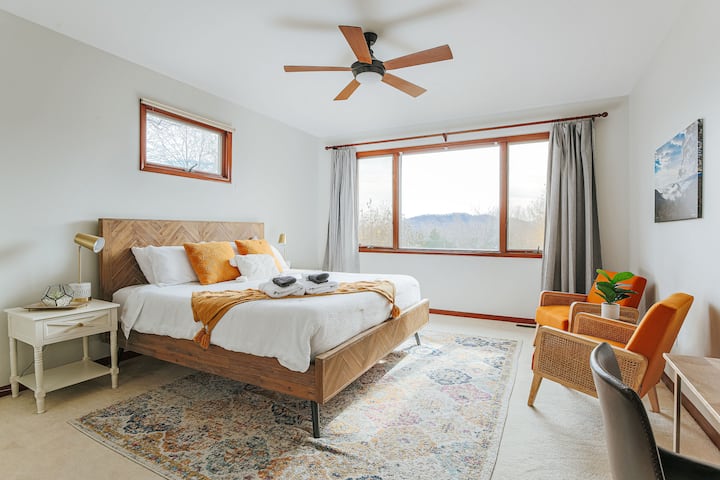 Master bedroom's California King bed and sitting area in front of bay windows with stunning views