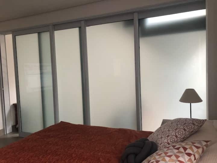 Апартманот на приземје е интегриран во дневната соба и е затворен со лизгачка врата со матирано стакло, одржувајќи ја приватноста без да се изгуби интеграцијата на околината. Има брачен кревет (широк 150-179 см) и бикама за влечење. Спалната соба и бањата се прилично големи.