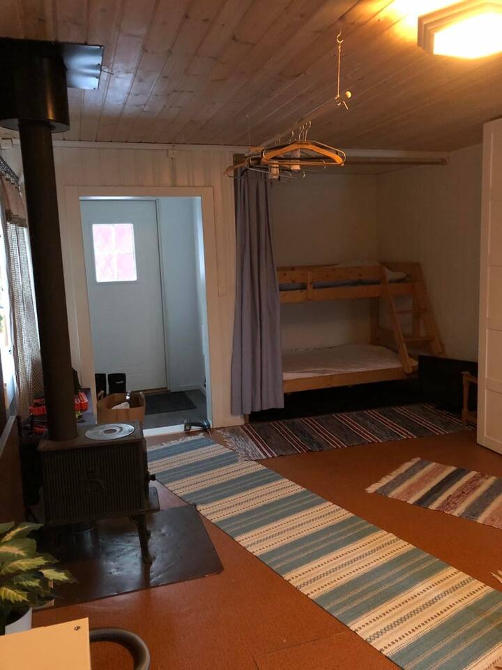 Den mellemliggende hytte, gang og stue med køjeseng. Pejs