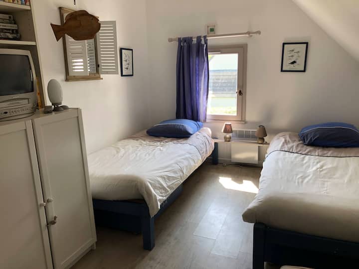 Chambre 2. Deux lits jumeaux avec chacun un tiroir disponible, des jeux pour les enfants dans le tiroir sous la fenêtre, des livres et cassettes vidéos dans le meuble blanc. Merci de ne pas emmener les animaux de compagnie dans les chambres.
