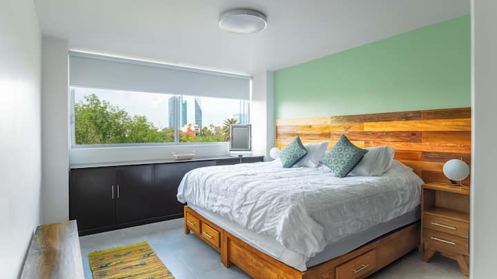 تطل غرفة النوم الرئيسية التي تحتوي على سرير كبير وحمام داخلي على متنزه بارك مكسيكو.