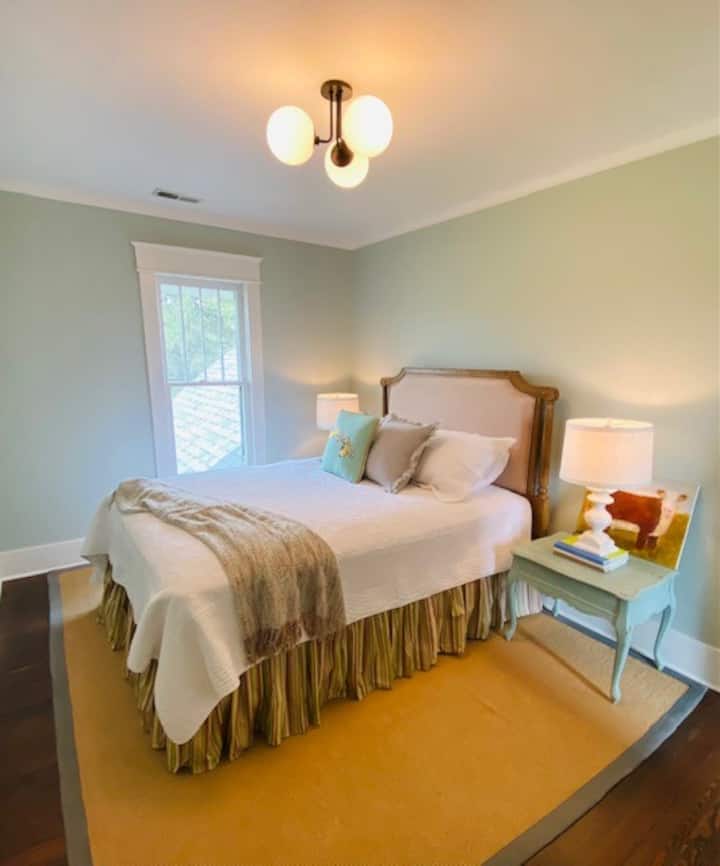 The secondary bedroom in the central part of the upstairs features a queen sized bed and  is trimmed out with beautiful linens, suitcase rack and reading lamps on the side tables.