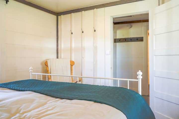 Main level master with Queen bed looking into closet/ storage room with glimpse of bathroom