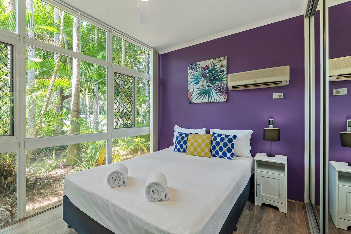 Спалня с двойно легло на долния етаж с големи плъзгащи се халати, климатик и вентилатор на тавана.