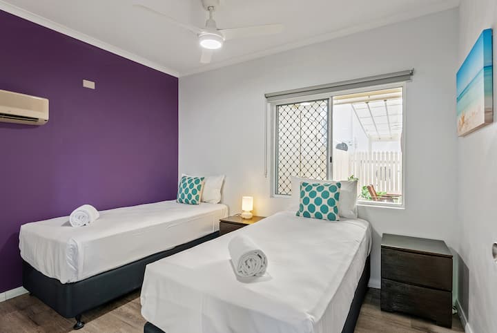Chambre au rez-de-chaussée avec 2 lits simples, de grands peignoirs intégrés et des tables d'appoint. Ventilateur de plafond et climatisation.