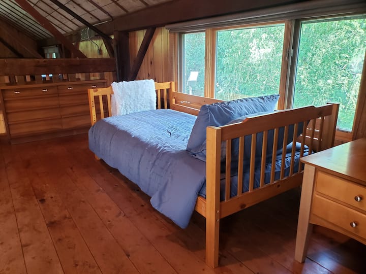 כל אחד מחדרי השינה הקטנים בלופט כולל מיטה זוגית, שידה ושידה ליד המיטה.