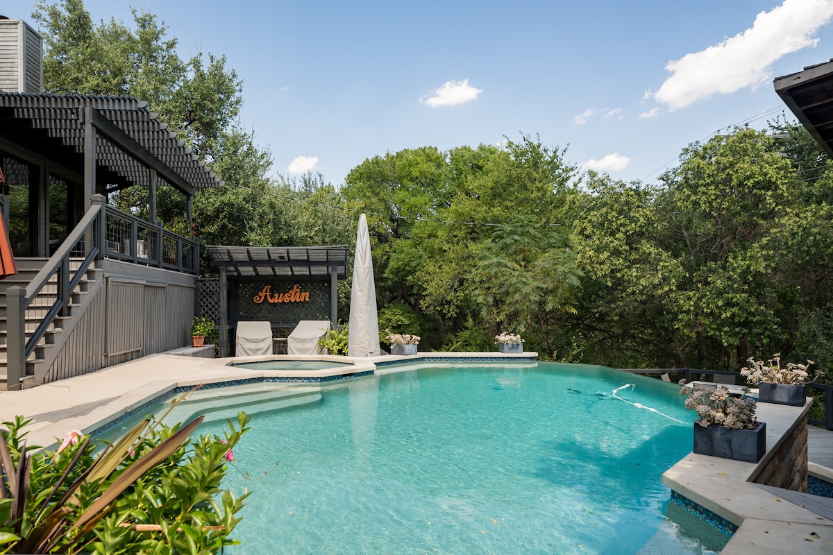 The inviting pool area features a shaped swimming pool surrounded by lush greenery, with two lounge chairs positioned nearby. A shaded cabana is situated to the left, enhancing the outdoor leisure space, while a welcoming sign displays 'Austin' in vibrant lettering.