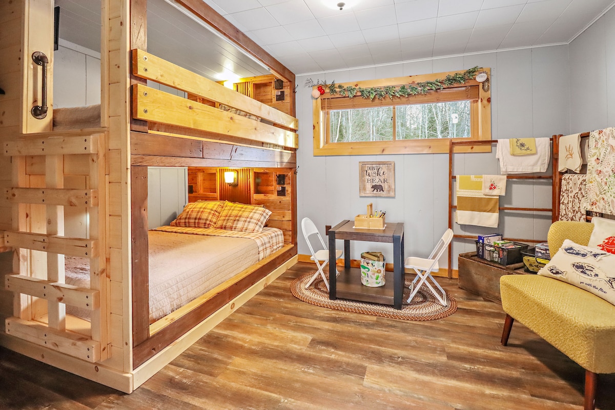 Dormitorio de nivel inferior. ¡Esta litera tamaño queen hecha a medida está repleta de cosas!  Cada uno ofrece dos pequeños cubículos para artículos personales como teléfonos celulares y carteras, una luz cálida con interruptor, enchufes regulares y USB, mini luces nocturnas Y televisores inteligentes de 24pulgadas.