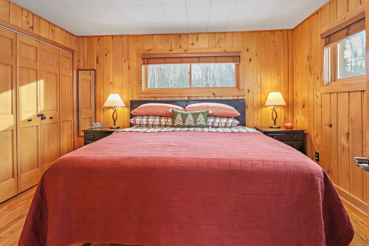 Habitación principal del nivel superior con cama king, oficina pequeña y TV inteligente.  Una zona colgante y estantes ofrecen espacio para guardar ropa durante tu estadía.  