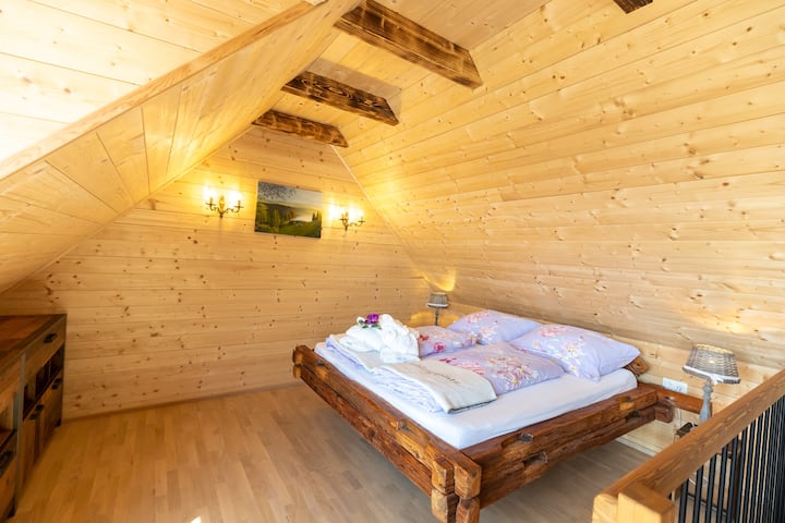 Una escalera de madera conduce a la habitación abierta Stadl, en la planta superior, que recuerda a un haystack tradicional. En la galería, puedes disfrutar de la vista a lo lejos con la puerta del balcón abierta, o sentarte en la silla de lectura y echarle un vistazo a la estantería