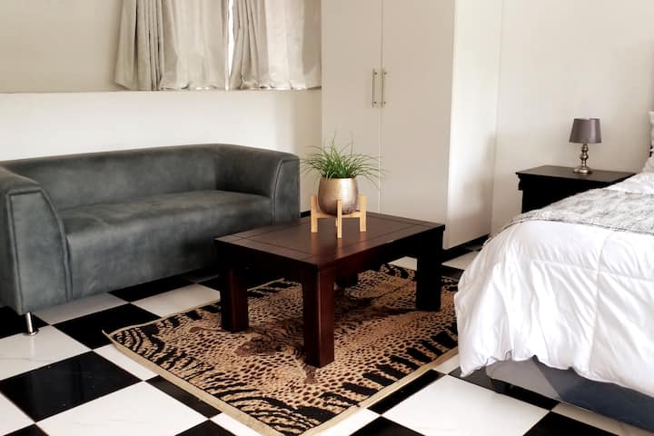 Sitting area with couch and coffee table. Wardbrobe and bedside lamp shown.