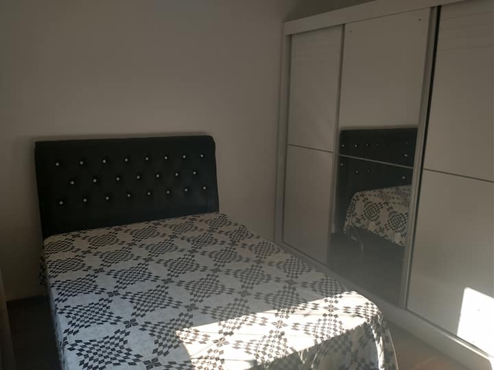 Habitación con una cama doble, ventilador, armario doble y vestidor a disposición del huésped.