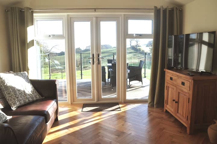 Rrezet e diellit përmbytin dhomën e ndenjjes duke krijuar një hapësirë të ngrohtë dhe komode, megjithatë nëse dielli nuk shkëlqen, vizitorët mund ta shijojnë televizorin e madh inteligjent. 