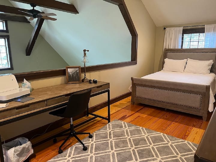 Spavaća soba u potkrovlju s bračnim krevetom i uredskim prostorom