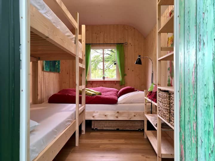 ორი ორსართულიანი საწოლი მარცხნივ და ფანჯრის ქვეშ ორადგილიანი საწოლი