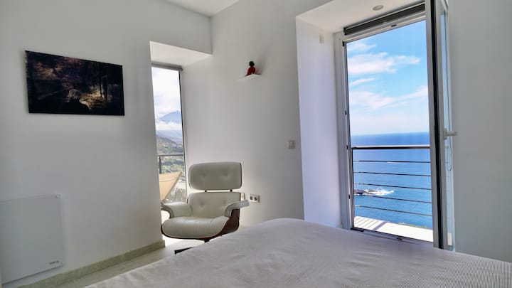 A bright bedroom with a balcony and window overlooking the Atlantic Ocean and Mount Teide.