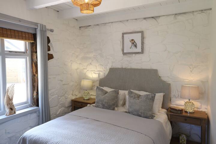 ห้องนอนชั้นล่างเตียงควีนไซส์ที่มีประตูเข้าสู่สวน